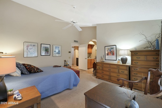 carpeted bedroom with ceiling fan, high vaulted ceiling, and ensuite bath