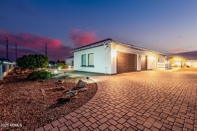 view of side of property featuring decorative driveway, a garage, and stucco siding