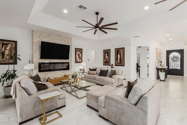 living room with a tray ceiling, visible vents, ceiling fan, and recessed lighting