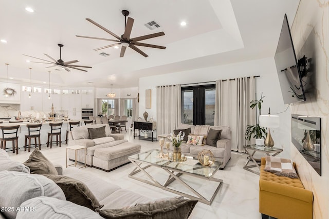 living room featuring a raised ceiling, recessed lighting, visible vents, and ceiling fan