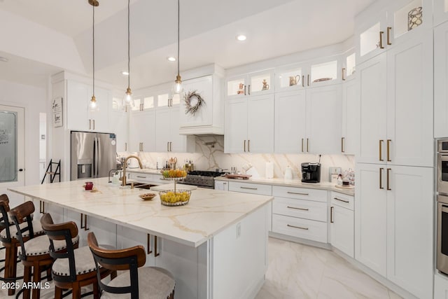 kitchen featuring marble finish floor, light stone counters, a kitchen breakfast bar, stainless steel appliances, and decorative backsplash