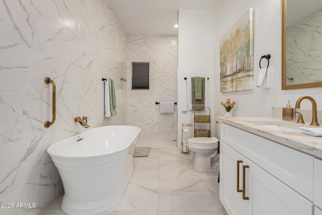 full bath featuring vanity, stone wall, a soaking tub, toilet, and marble finish floor