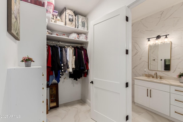 bathroom featuring a spacious closet, marble finish floor, and vanity