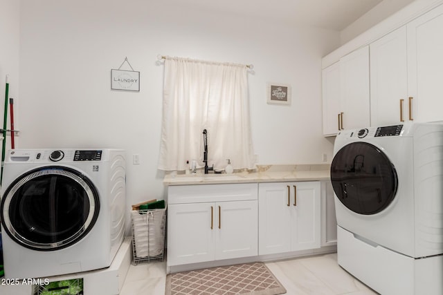 laundry room with cabinet space, washing machine and dryer, and a sink