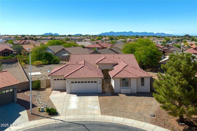 mediterranean / spanish-style home featuring an attached garage, stucco siding, a tile roof, and a residential view