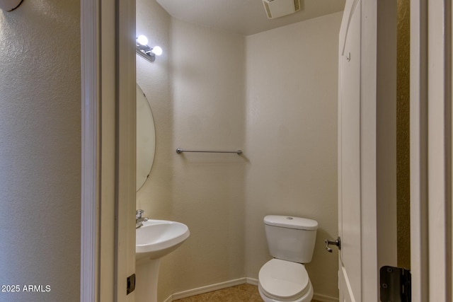 bathroom with toilet, baseboards, visible vents, and a sink
