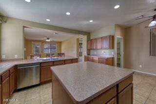 kitchen with stainless steel dishwasher, brown cabinetry, and light tile patterned flooring