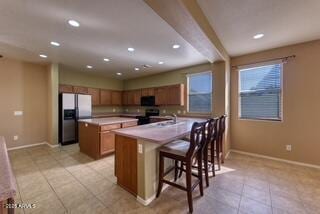 kitchen featuring baseboards, brown cabinets, and refrigerator with ice dispenser