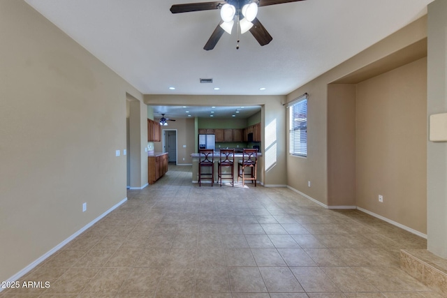 living area with light tile patterned floors, visible vents, baseboards, and a ceiling fan