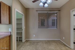 unfurnished dining area with a ceiling fan, light carpet, and baseboards