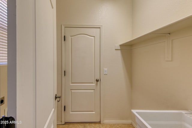 clothes washing area with laundry area, electric dryer hookup, light tile patterned flooring, and baseboards