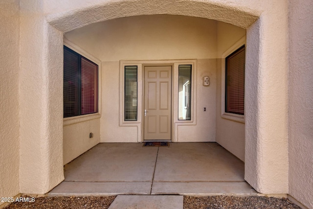 property entrance with stucco siding and a patio