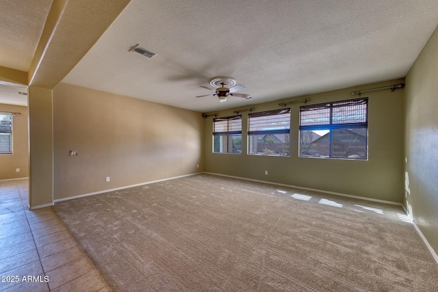 spare room with a textured ceiling, baseboards, a ceiling fan, and visible vents
