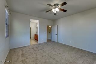 unfurnished bedroom featuring ensuite bath, baseboards, ceiling fan, and carpet floors