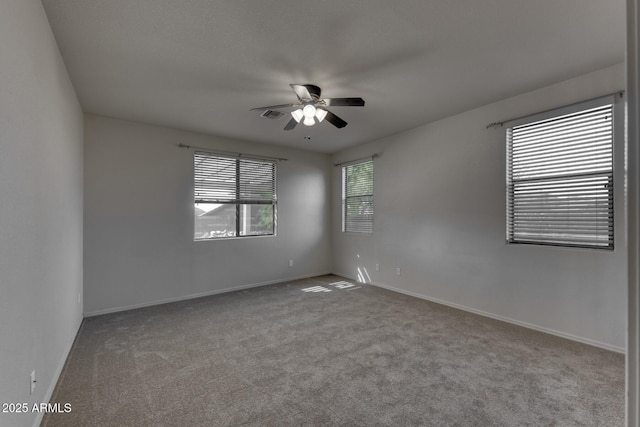 carpeted spare room featuring visible vents, baseboards, and a ceiling fan
