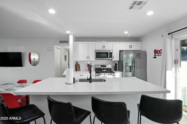 kitchen with appliances with stainless steel finishes, sink, a breakfast bar area, and white cabinets