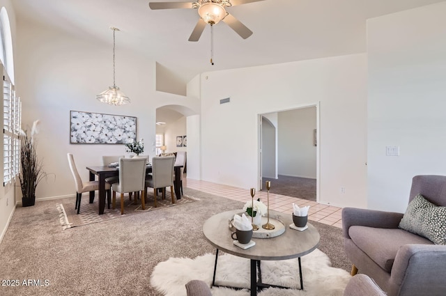 tiled living room featuring ceiling fan with notable chandelier and lofted ceiling