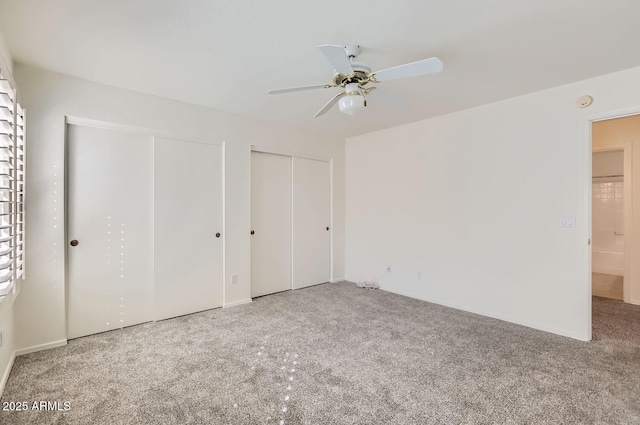 unfurnished bedroom with ceiling fan, multiple closets, and carpet floors