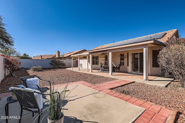 back of house featuring a patio area and solar panels