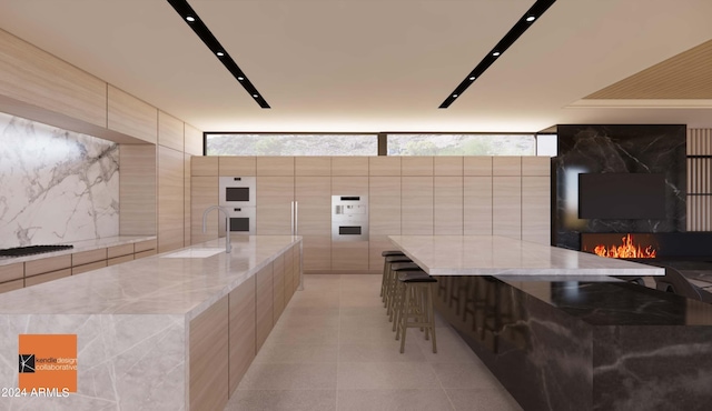 kitchen featuring sink, a large island, tile walls, floor to ceiling windows, and a breakfast bar area