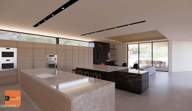 kitchen with a spacious island, light stone counters, and floor to ceiling windows