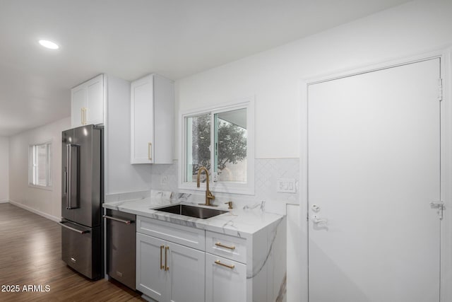 kitchen with sink, light stone counters, appliances with stainless steel finishes, dark hardwood / wood-style flooring, and white cabinets