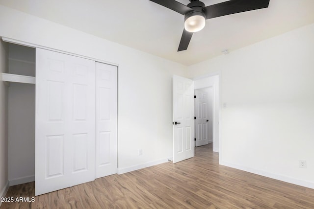 unfurnished bedroom featuring hardwood / wood-style floors, ceiling fan, and a closet