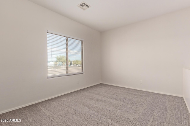 carpeted spare room featuring visible vents and baseboards