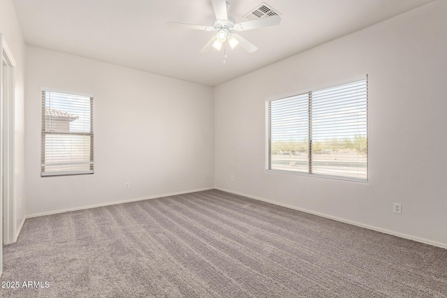 unfurnished room with a wealth of natural light, visible vents, carpet floors, and a ceiling fan