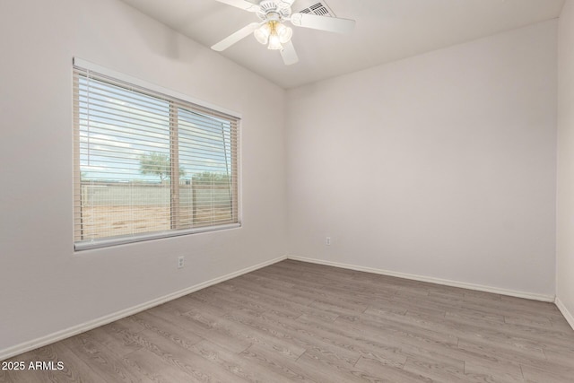 spare room with a ceiling fan, wood finished floors, and baseboards