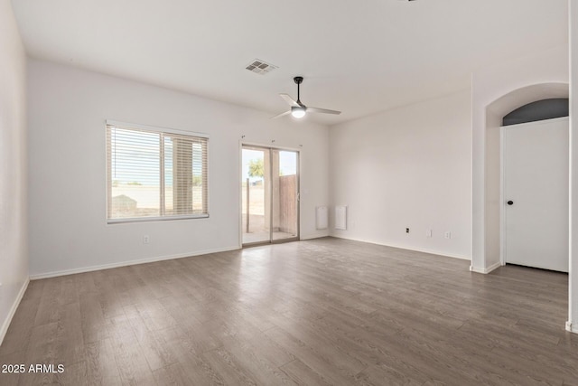 unfurnished room with a ceiling fan, wood finished floors, visible vents, and baseboards