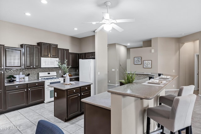2260 E Binner Dr, Chandler, AZ 85225 - kitchen featuring a center island, backsplash, white appliances, ceiling fan, and a breakfast bar