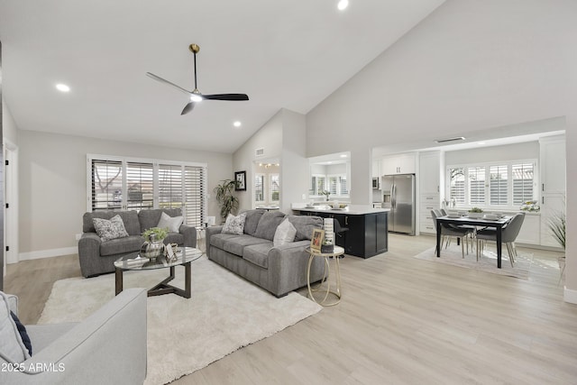 living room with ceiling fan, plenty of natural light, high vaulted ceiling, and light wood-type flooring