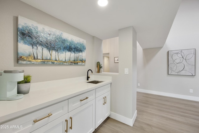 bar featuring white cabinetry, sink, and light hardwood / wood-style flooring