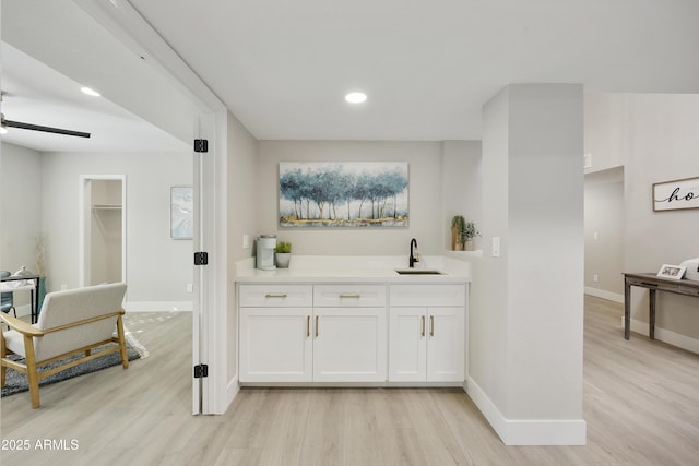 bar featuring white cabinetry, sink, ceiling fan, and light wood-type flooring