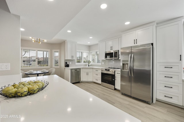 kitchen with tasteful backsplash, appliances with stainless steel finishes, sink, and white cabinets