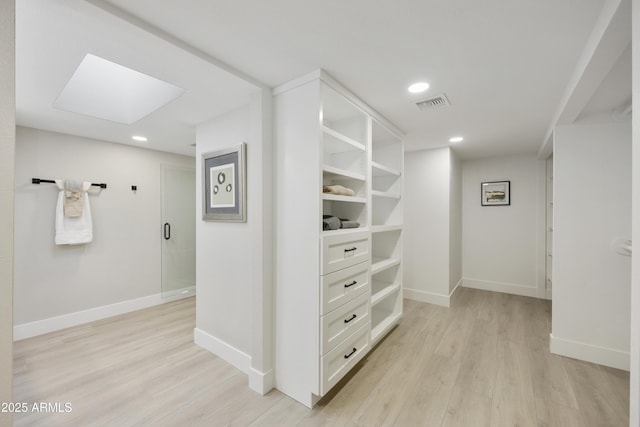 walk in closet featuring a skylight and light hardwood / wood-style floors