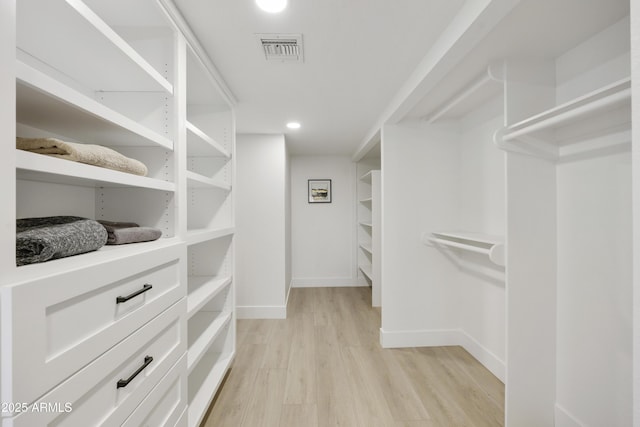 walk in closet with light hardwood / wood-style flooring