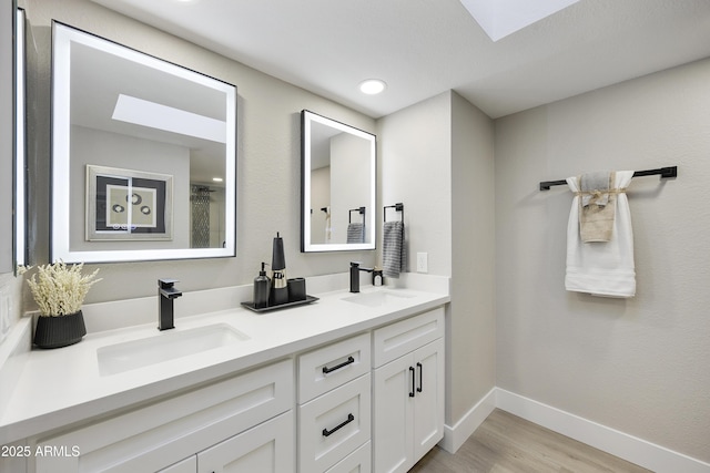 bathroom with vanity, hardwood / wood-style flooring, and a skylight