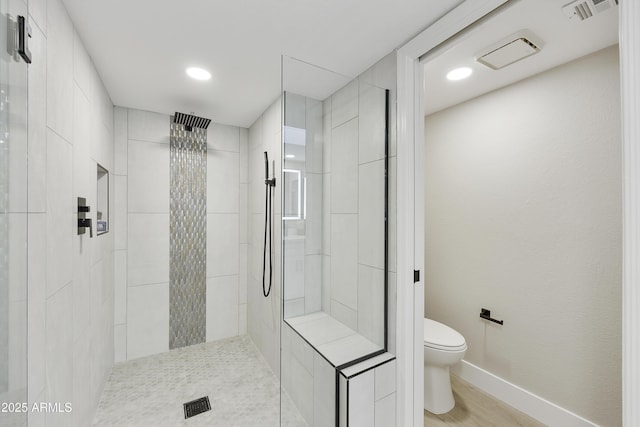 bathroom with hardwood / wood-style flooring, tiled shower, and toilet