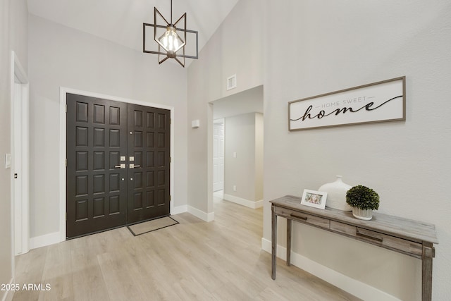 foyer entrance featuring a high ceiling, a chandelier, and light hardwood / wood-style flooring