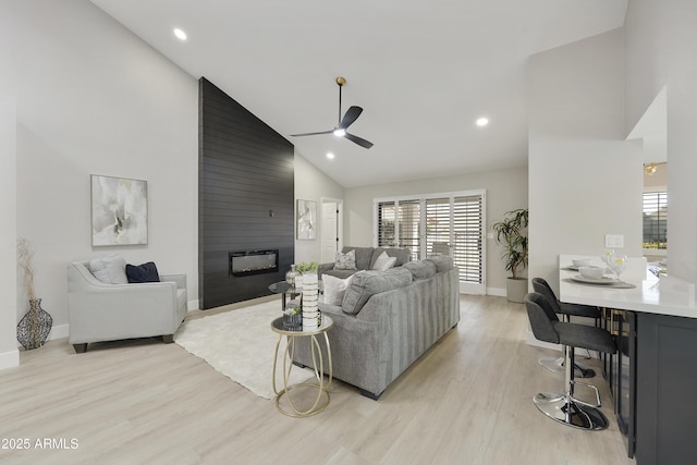 living room with a large fireplace, plenty of natural light, high vaulted ceiling, and light hardwood / wood-style floors