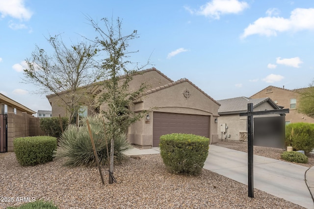 mediterranean / spanish-style home with fence, a tiled roof, stucco siding, a garage, and driveway