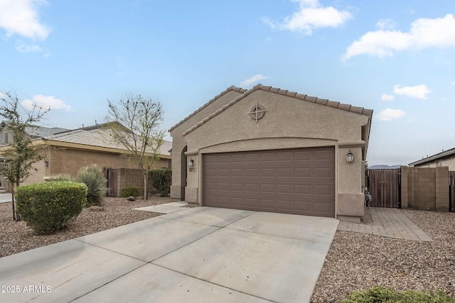 view of front of house featuring fence, a garage, driveway, and stucco siding