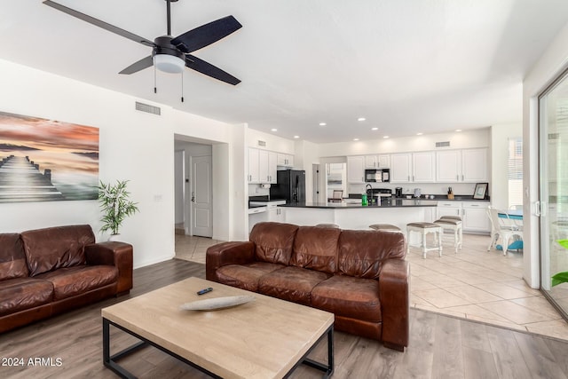 living room with ceiling fan and light hardwood / wood-style flooring