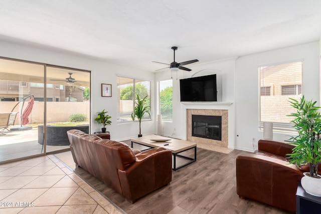 living room featuring ceiling fan, a fireplace, and light hardwood / wood-style floors