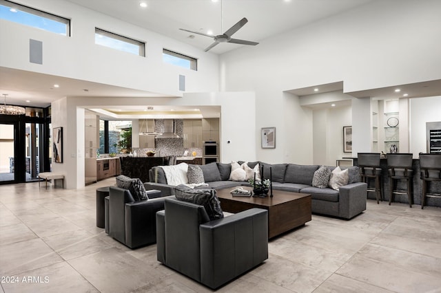 living room featuring a high ceiling and ceiling fan with notable chandelier