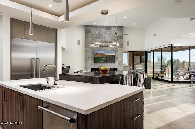 kitchen with sink, light tile patterned floors, dark brown cabinets, a large fireplace, and stainless steel appliances