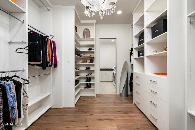 spacious closet with an inviting chandelier, light hardwood / wood-style flooring, and sink