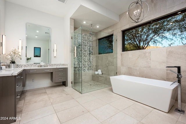 bathroom with vanity, independent shower and bath, tile walls, and a notable chandelier